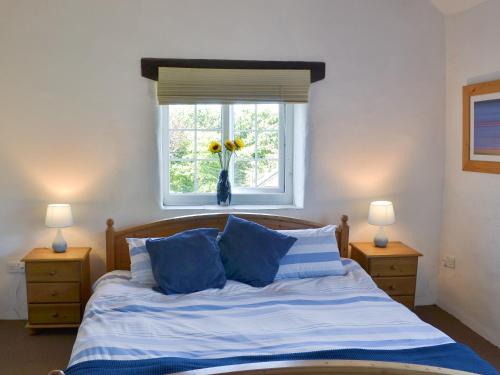 a bedroom with a bed with blue pillows and a window at Wallhouse Barn in Blisland