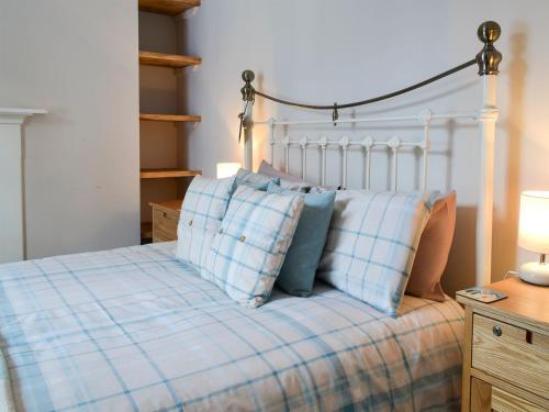 a bed with blue and white plaid pillows on it at Melrose Cottage in Cromer