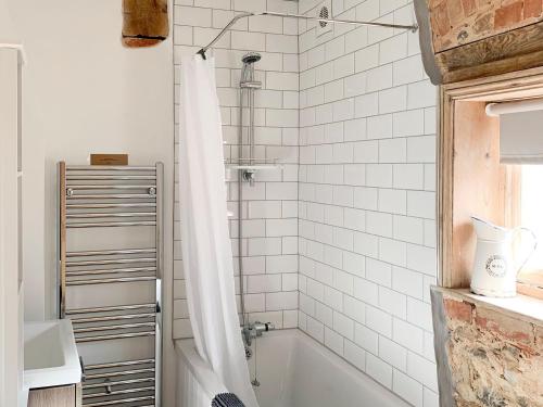 a bathroom with a bath tub with a shower curtain at Melrose Cottage in Cromer