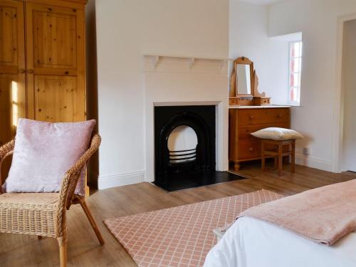 a room with a fireplace and a chair and a bed at The Cottage At 1710 in Castle Carrock