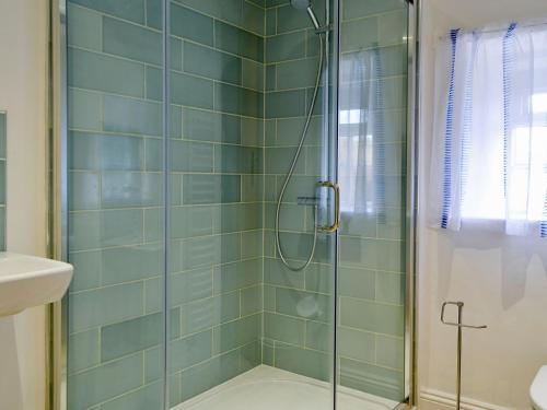 a bathroom with a shower with blue tiles at The Cottage At 1710 in Castle Carrock