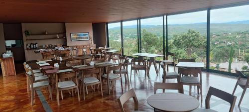 a restaurant with tables and chairs and large windows at Vila Toá in Alto Paraíso de Goiás