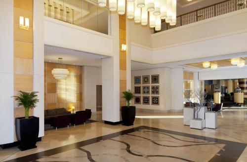 a lobby with palm trees in the middle of a building at Mak Albania Hotel in Tirana
