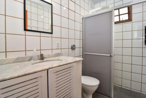 y baño con lavabo, aseo y espejo. en Casa de Praia a 250 mts da Avenida das Rendeiras, Lagoa da Conceição P1716, en Florianópolis