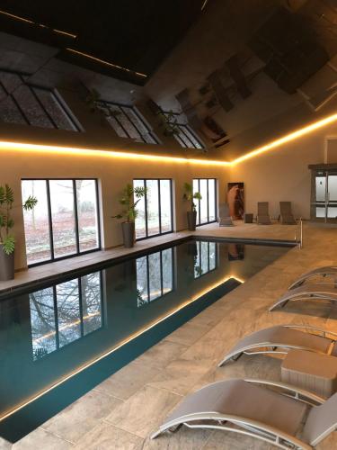 a swimming pool with chairs in a room with windows at Burton Lodge Guest House & Spa in Brandesburton