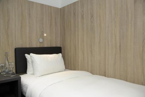 a bedroom with a white bed and a wooden wall at The Z Hotel Shoreditch in London