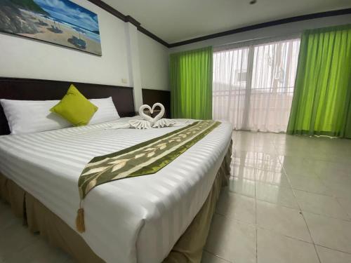 a bedroom with a large bed with green curtains at Sue@Cozy Guesthouse in Kata Beach