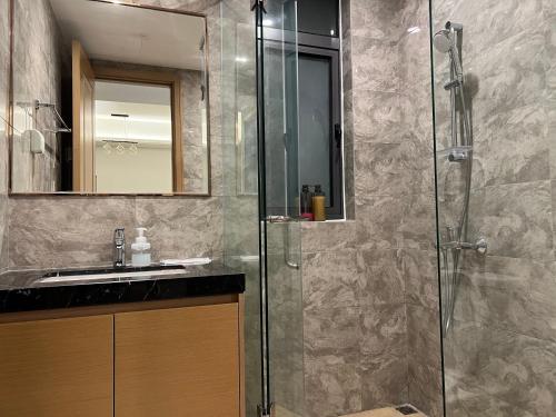 a bathroom with a glass shower and a sink at R&F Princess Cove by GreatDay in Johor Bahru