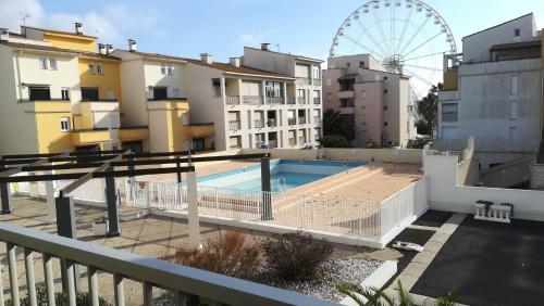 een uitzicht op een gebouw met een zwembad en een reuzenrad bij Beau studio cabine avec balcon, vue piscine, parking privé, climatisation, solarium, laverie in Cap d'Agde