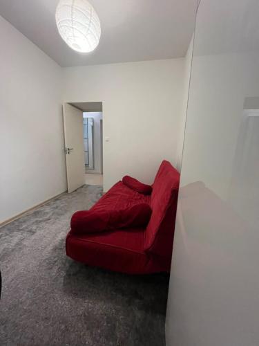 czerwona kanapa siedząca w pokoju ze ścianą w obiekcie Apartament Szczęśliwicka w Warszawie