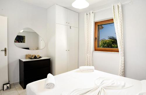 a white bedroom with a bed and a mirror at Valia-Sunset in Plakias