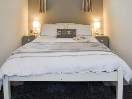 een slaapkamer met een groot wit bed met 2 lampen bij Clinton Cottage in Yaxham