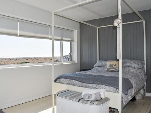 ein Schlafzimmer mit einem Himmelbett und einem Fenster in der Unterkunft Gull House in Dungeness