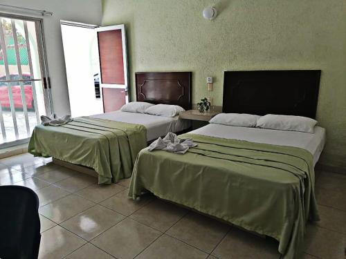 two beds in a hotel room with a window at Hotel Rio Balsas in Manzanillo