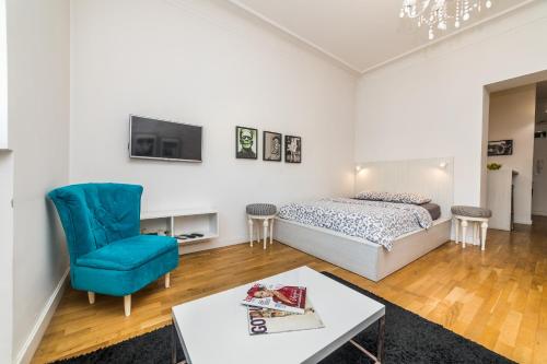 een slaapkamer met een bed en een blauwe stoel bij Marcel Apartments in Belgrado
