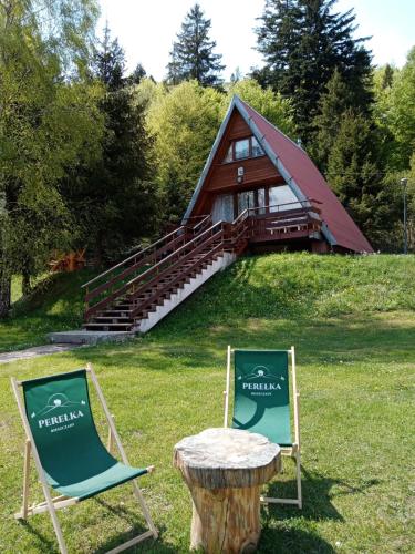 two chairs and a table in front of a cabin at Perełka Bieszczady Domki in Cisna