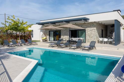 una piscina con sillas y una casa en "Casa Mia" Luxury villa with heated swimming pool with jacuzzi, en Šestanovac