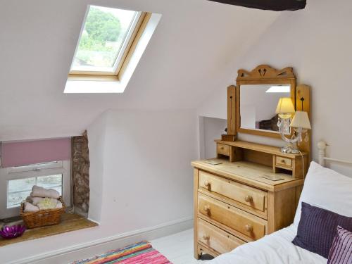 een slaapkamer met een spiegel en een houten dressoir bij Ash Cottage in Tideswell