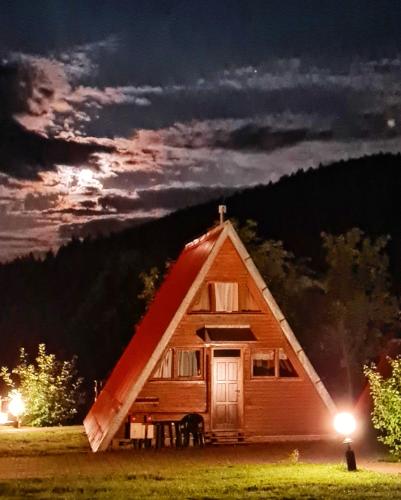 a cabin with a red roof at night at Perełka Bieszczady Domki in Cisna