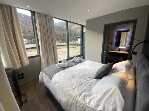 une chambre avec un lit et une grande fenêtre dans l'établissement AU JARDIN DU CLOS, à Brides-les-Bains