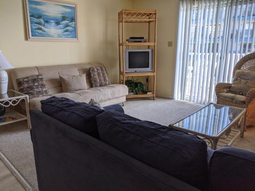 a living room with a couch and a tv at Marylander Condominiums, 90 steps from the beach in Ocean City