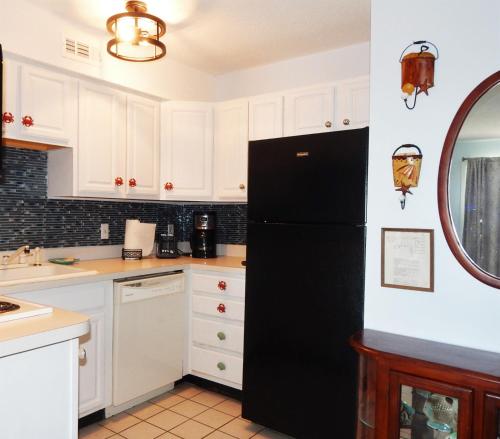 a black refrigerator in a kitchen with white cabinets at Marylander Condominiums, 90 steps from the beach in Ocean City