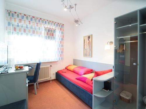 a small bedroom with a bed and a desk and a desk at Hotel Restaurant Krehl's Linde in Stuttgart