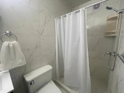 y baño con cortina de ducha blanca y aseo. en (27) Acogedor Dpto en Miraflores, en Lima