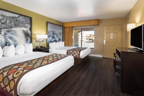 a hotel room with two beds and a flat screen tv at Super 8 by Wyndham NAU/Downtown Conference Center in Flagstaff