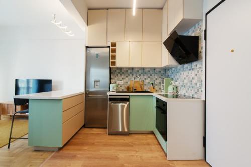 Una cocina con gabinetes blancos y un refrigerador de acero inoxidable. en Luxury 1-Bedroom Apartment by the Sea in Athens, en Atenas