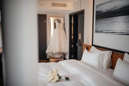 a wedding dress hanging in a bedroom with a bed at MERCURE KLAIPEDA CITY HOTEL, Meetings, Events, Restaurant & Bar - Accor Group, Pet Stay FREE in Klaipėda