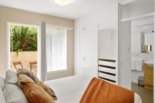 een witte slaapkamer met een bank en een raam bij King Bed, Water Views, Private Parking, Courtyard Living in the Heart of Sandy Bay in Sandy Bay