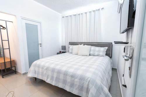 a white bedroom with a bed and a tv at Aquaville Dorado Moderna Villa 4 in Dorado