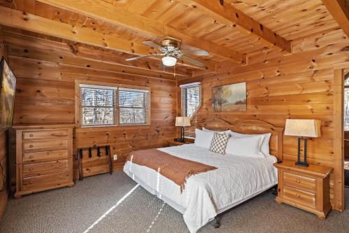 Dormitorio en cabaña de madera con cama y ventilador de techo en SunnySierra Cabin, en Sevierville