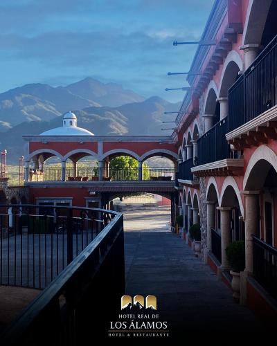 a building with a bridge and mountains in the background at Hotel Real de los Alamos in Álamos