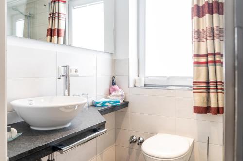 a bathroom with a sink and a toilet and a window at Hotel Restaurant Krehl's Linde in Stuttgart