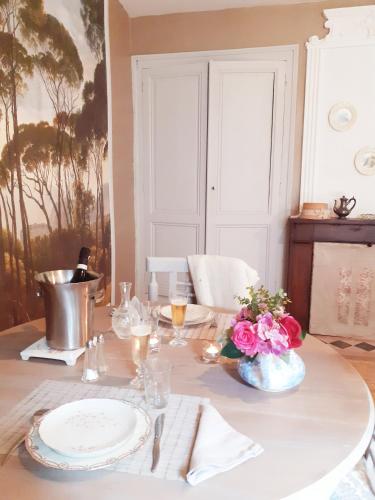 une table avec un chiffon de table blanc et des fleurs sur elle dans l'établissement Logis des Lugats, gite de charme, à La Réole