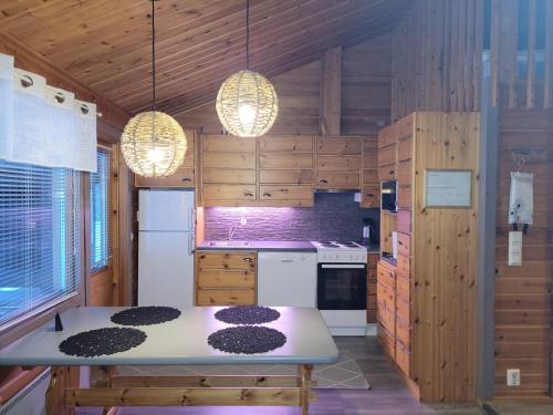 eine Küche mit Holzschränken, einem Tisch und 2 Leuchten in der Unterkunft Vuosselintähti 8 B in Ruka