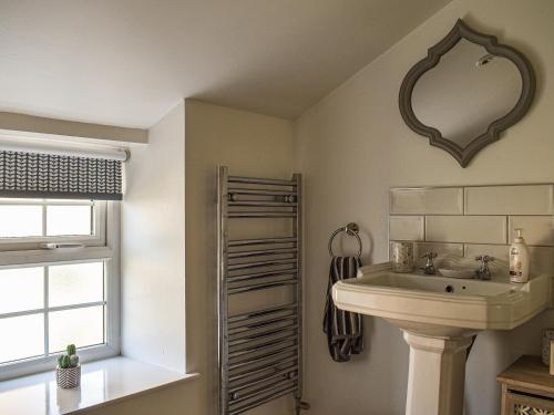 łazienka z umywalką i lustrem na ścianie w obiekcie Bathurst Cottage w mieście Scarcliffe