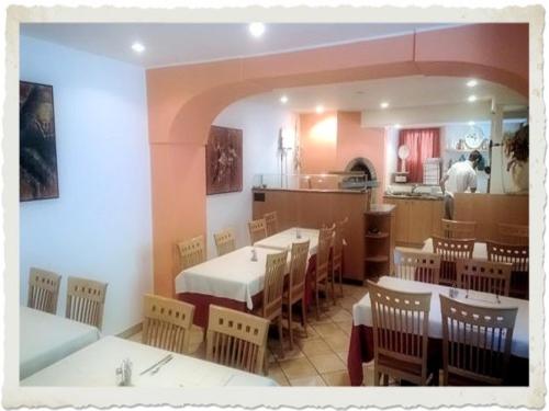 Un restaurante con mesas y sillas y una cocina. en Ristorante Dosso, en Sigirino