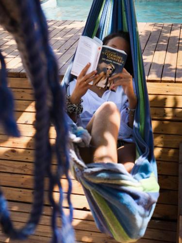 a woman sitting in a hammock reading a book at Dar Mar Hostel & Coworking in Paje