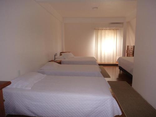 a hotel room with three beds and a window at ROSA CORTIANA Escalera in São Gabriel