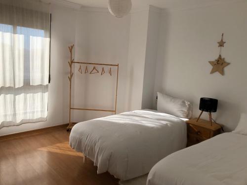 a white bedroom with two beds and a window at Apartamento anida in Granada