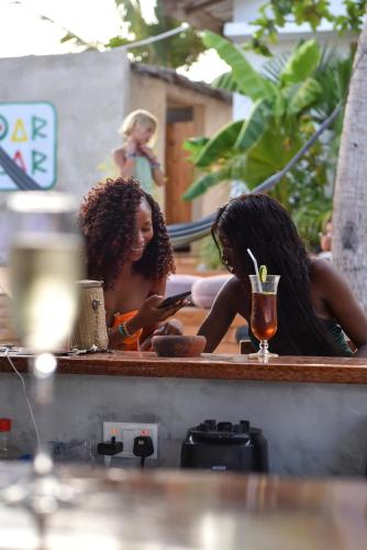 two women are looking at a cell phone at Dar Mar Hostel & Coworking in Paje