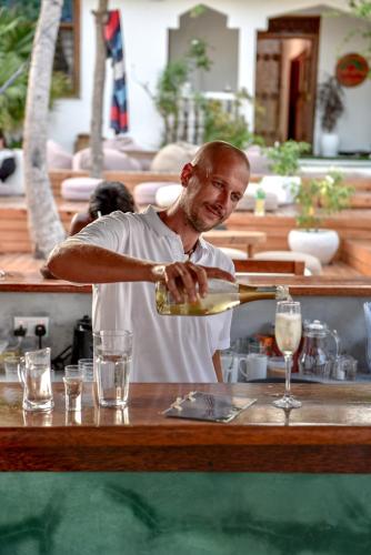 a man pouring champagne into a glass at a bar at Dar Mar Hostel & Coworking in Paje