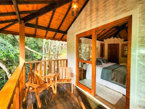 ein Schlafzimmer und ein Bett auf einer Veranda eines Hauses in der Unterkunft Pousada Cabana na Floresta - Monte Verde in Camanducaia
