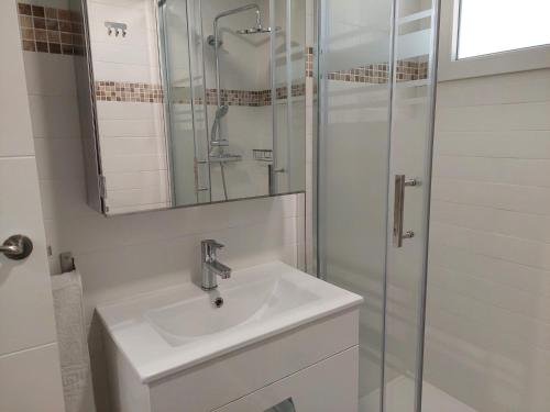 a white bathroom with a sink and a shower at Hostal GARDEN ROUS in Paiporta