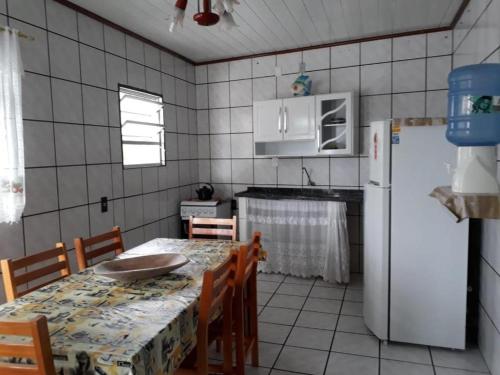 a kitchen with a table and a white refrigerator at Olhar da Barra Hospedagem - Casa Branca in Florianópolis