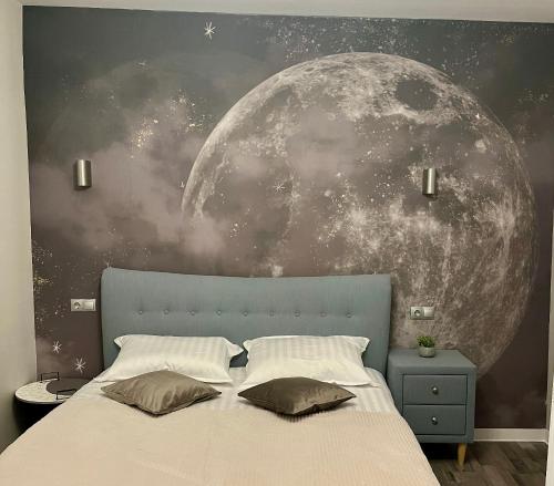 a bedroom with a bed with a mural of the moon at Moon and Sun Apartments in Sibiu