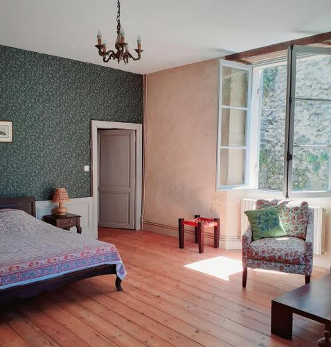 une chambre avec un lit, une chaise et une fenêtre dans l'établissement Logis des Lugats, gite de charme, à La Réole